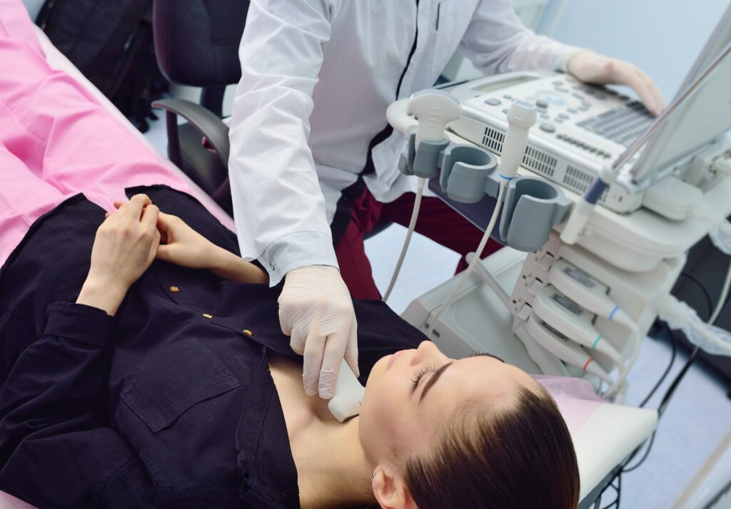 doctor examines the patient's thyroid gland on an ultrasound machine